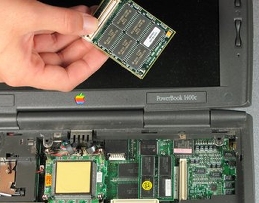 Holding the memory upgrade for an Apple Powerbook 1400c laptop.